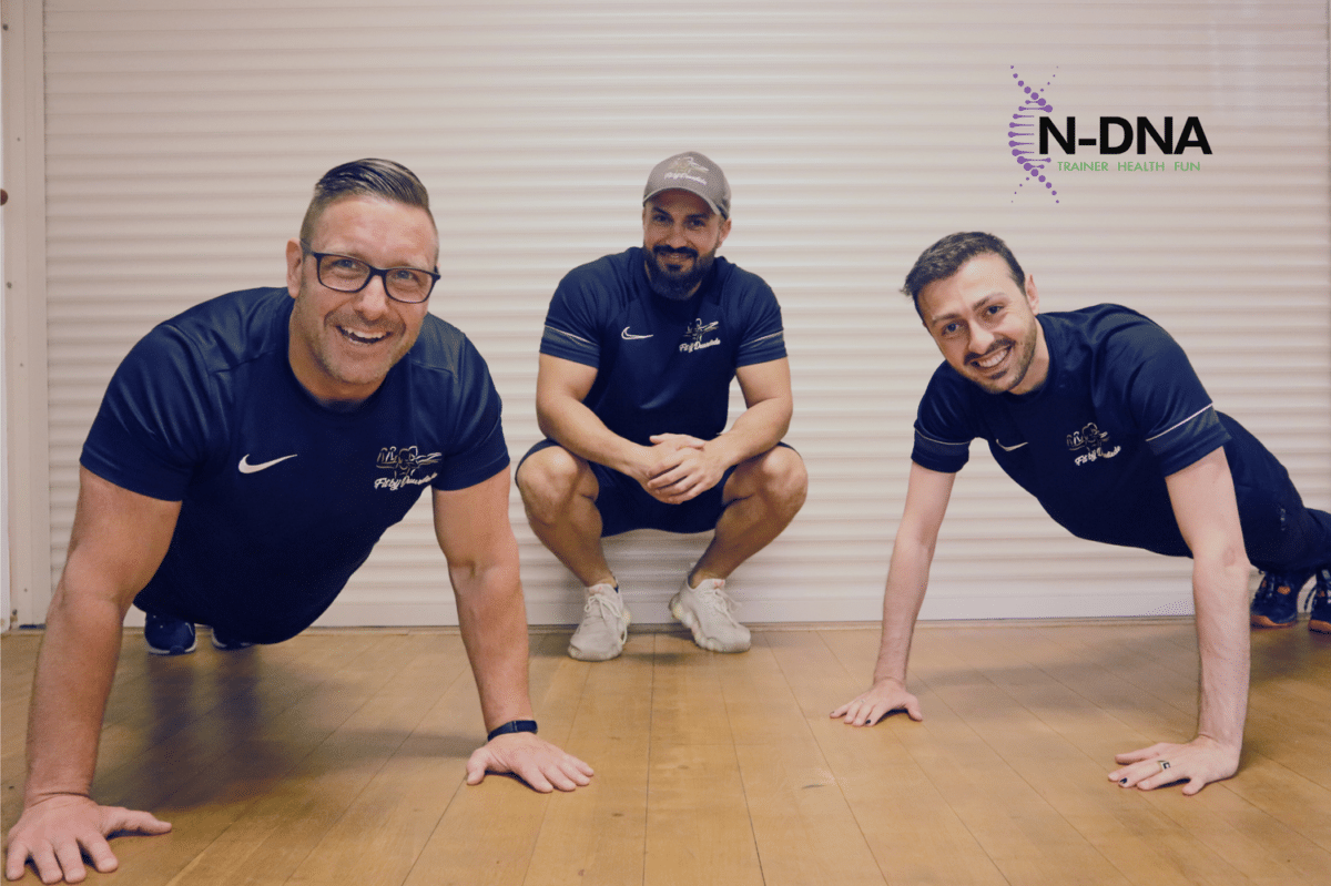 Drie vrolijke trainers op de foto, waarvan Nidjat die aan het opdrukken is.