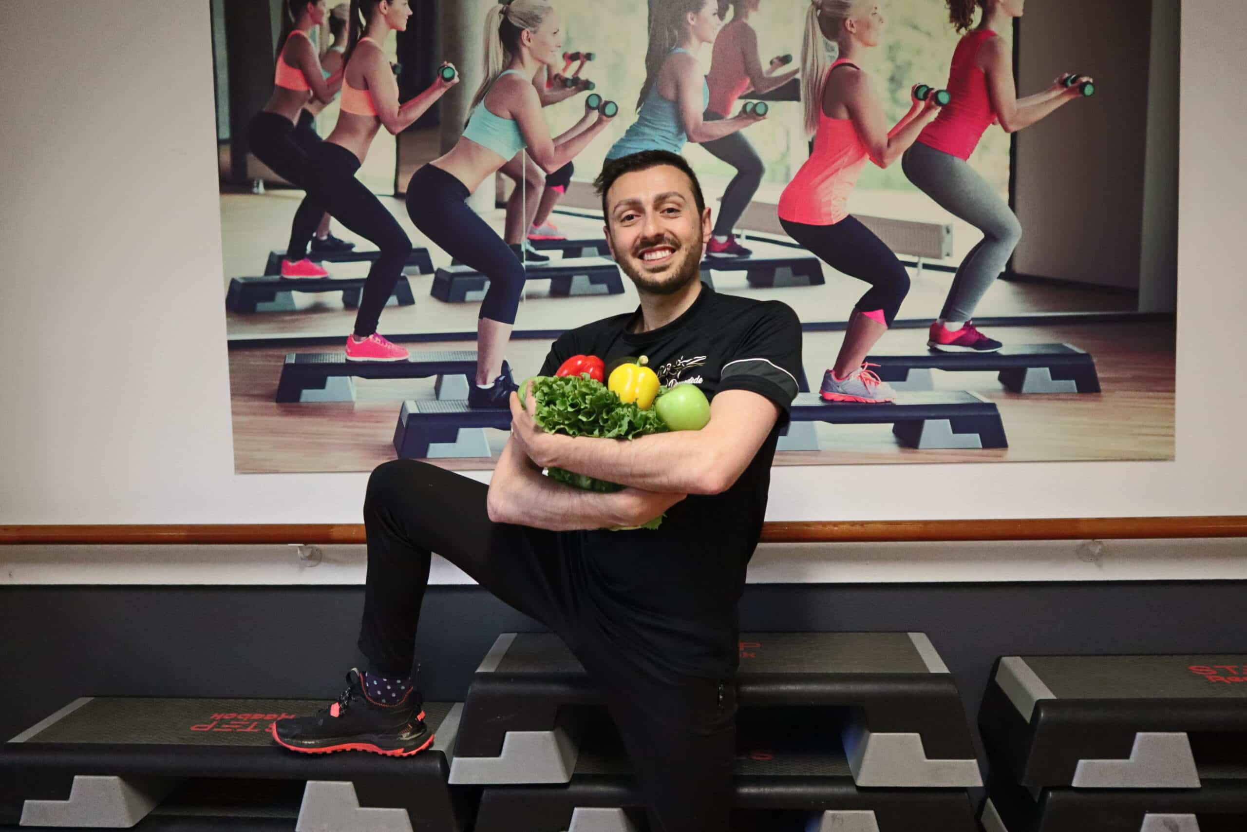 Vrolijke Nidjat die sportief gekleed is en houd groentes vast in zijn armen.