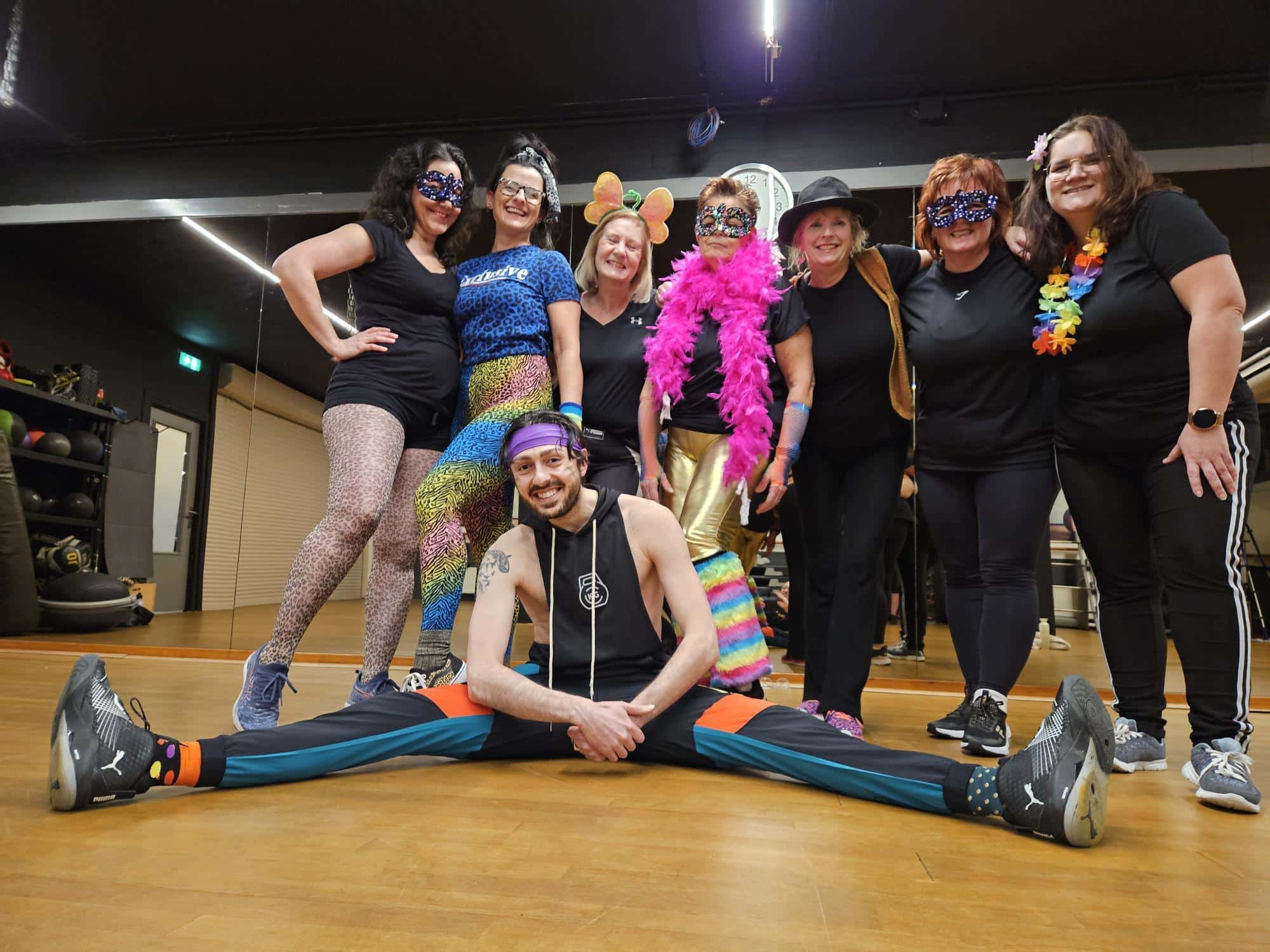 Groepje deelnemers die verkleed zijn voor thema carnaval in een Zumba les met de N-DNA Trainer.